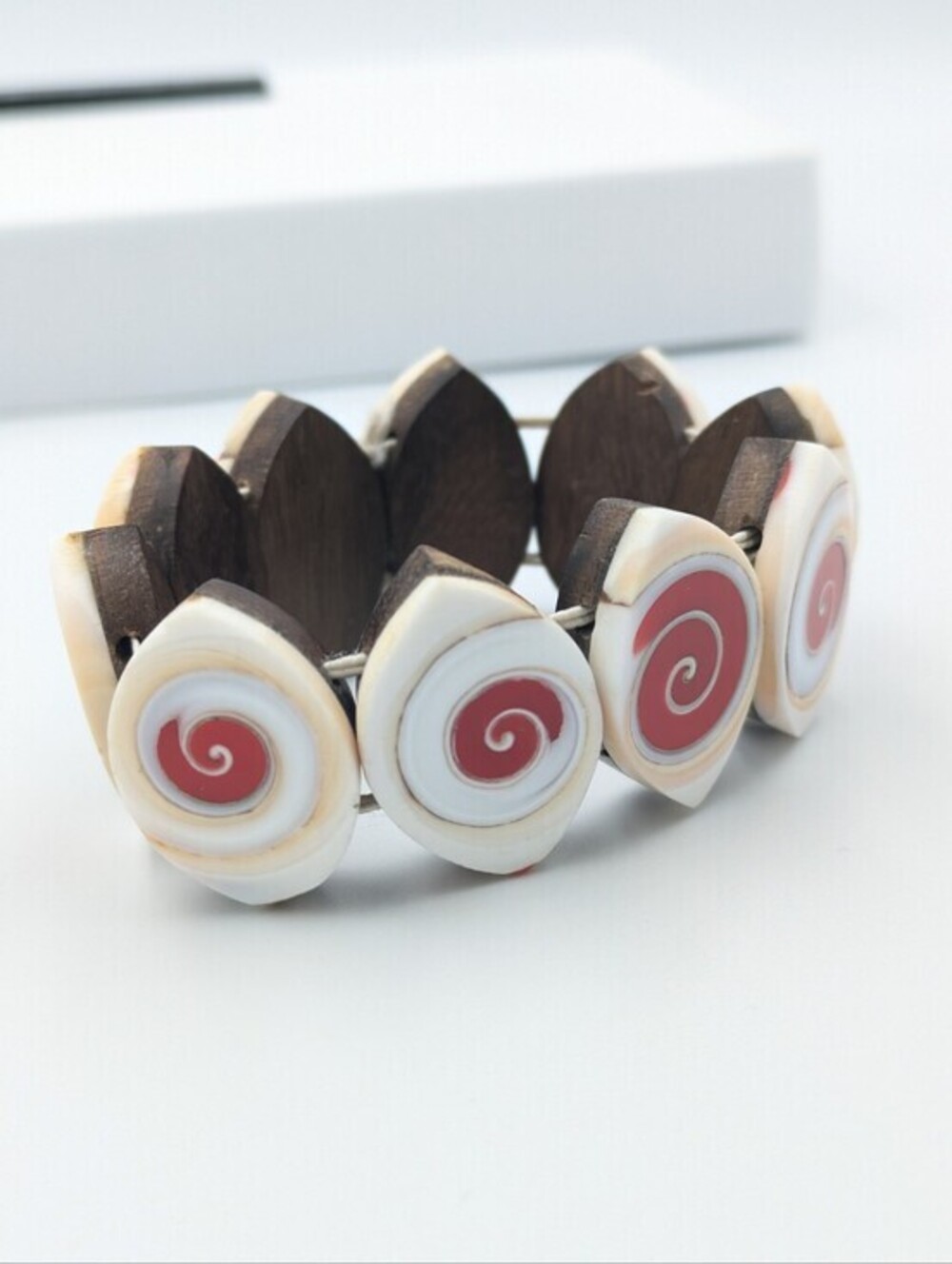 Stretch bracelet natural shells with vibrant red inlays back by a dark wood